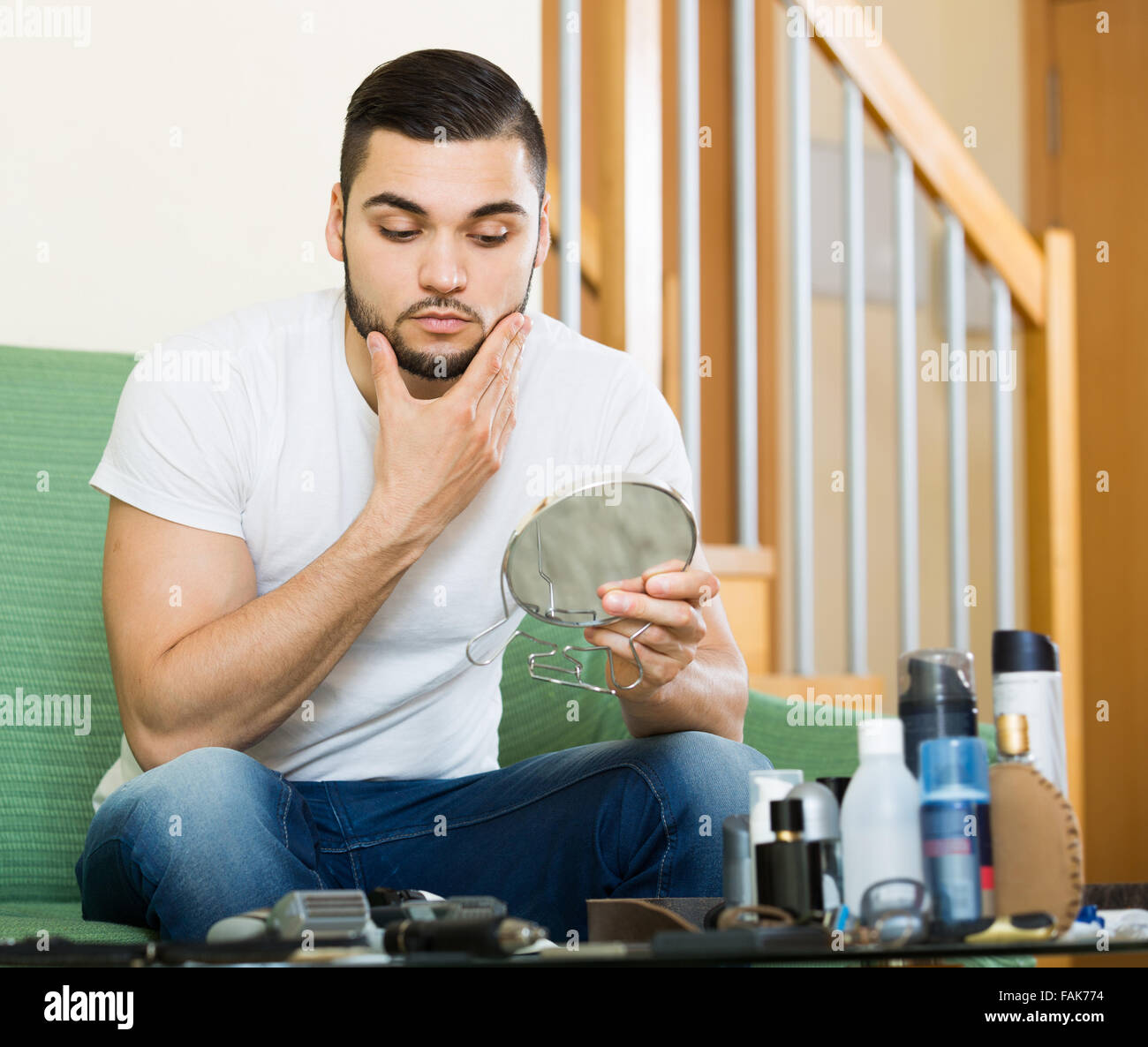 handsome guy looking at his problematic skin in a mirror Stock Photo