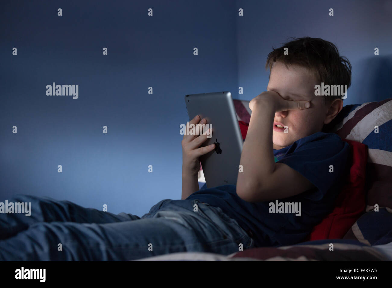 Online bullying Cyber bullying photo of an upset boy in his bedroom looking at hurtful messages on social media Stock Photo