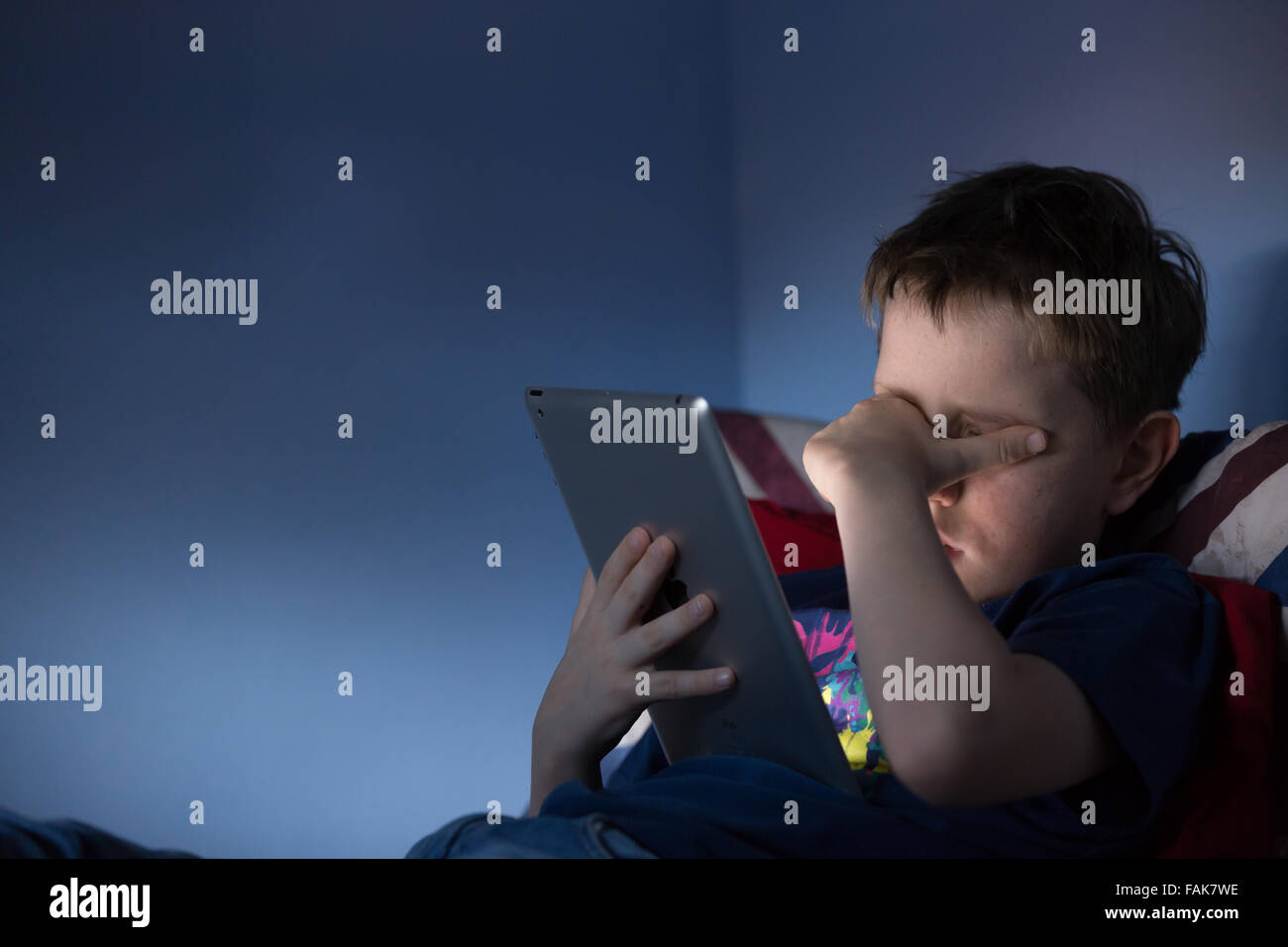 Online bullying Cyber bullying photo of an upset boy in his bedroom looking at hurtful messages on social media Stock Photo