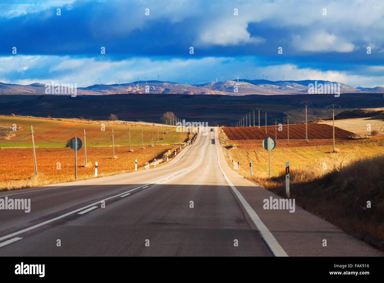 Landscape with road among fields and hills under cloudy sky Stock Photo ...