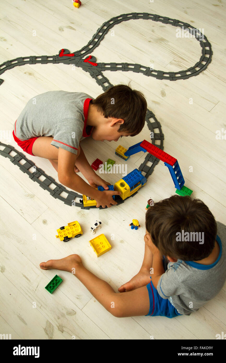 Toddler boys playing with toy train set. Stock Photo
