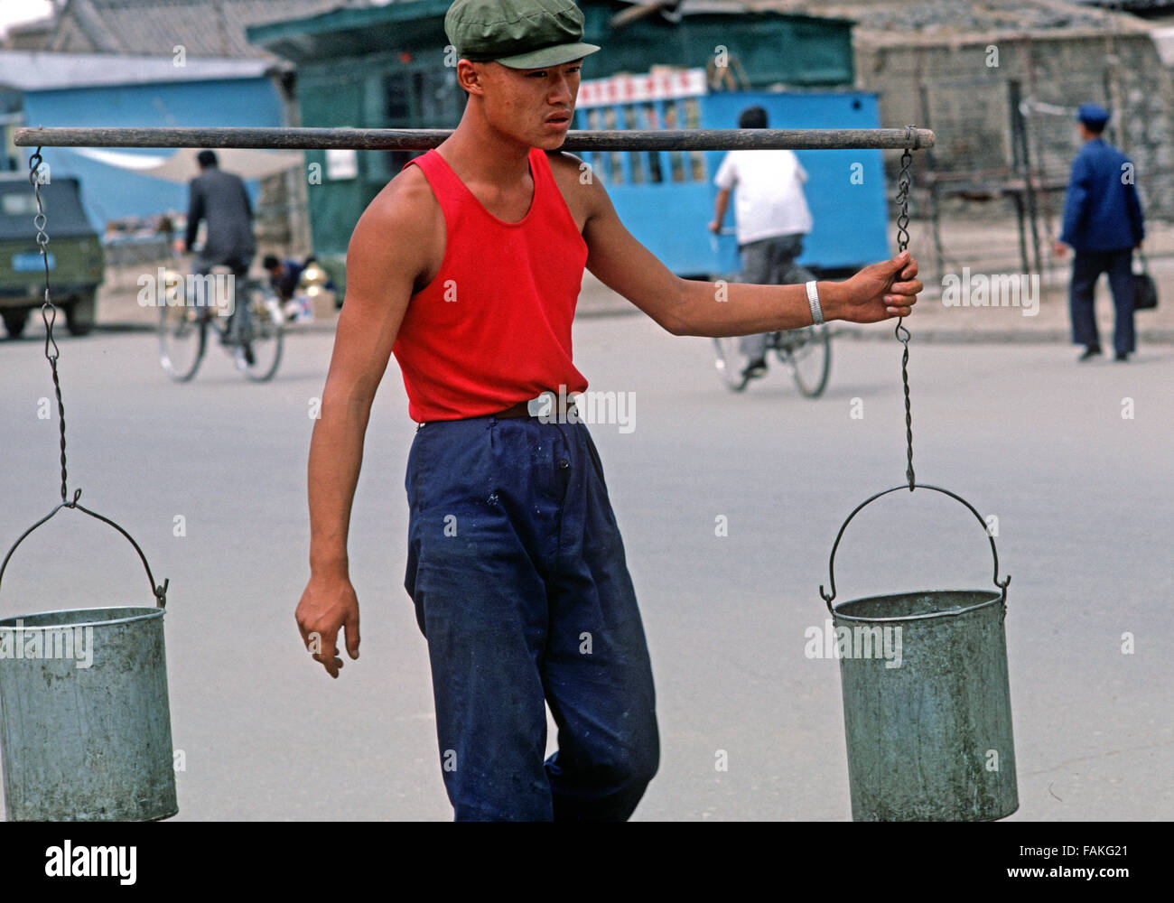 man carrying buckets of water on bamboo pole in Hohhot, capital of