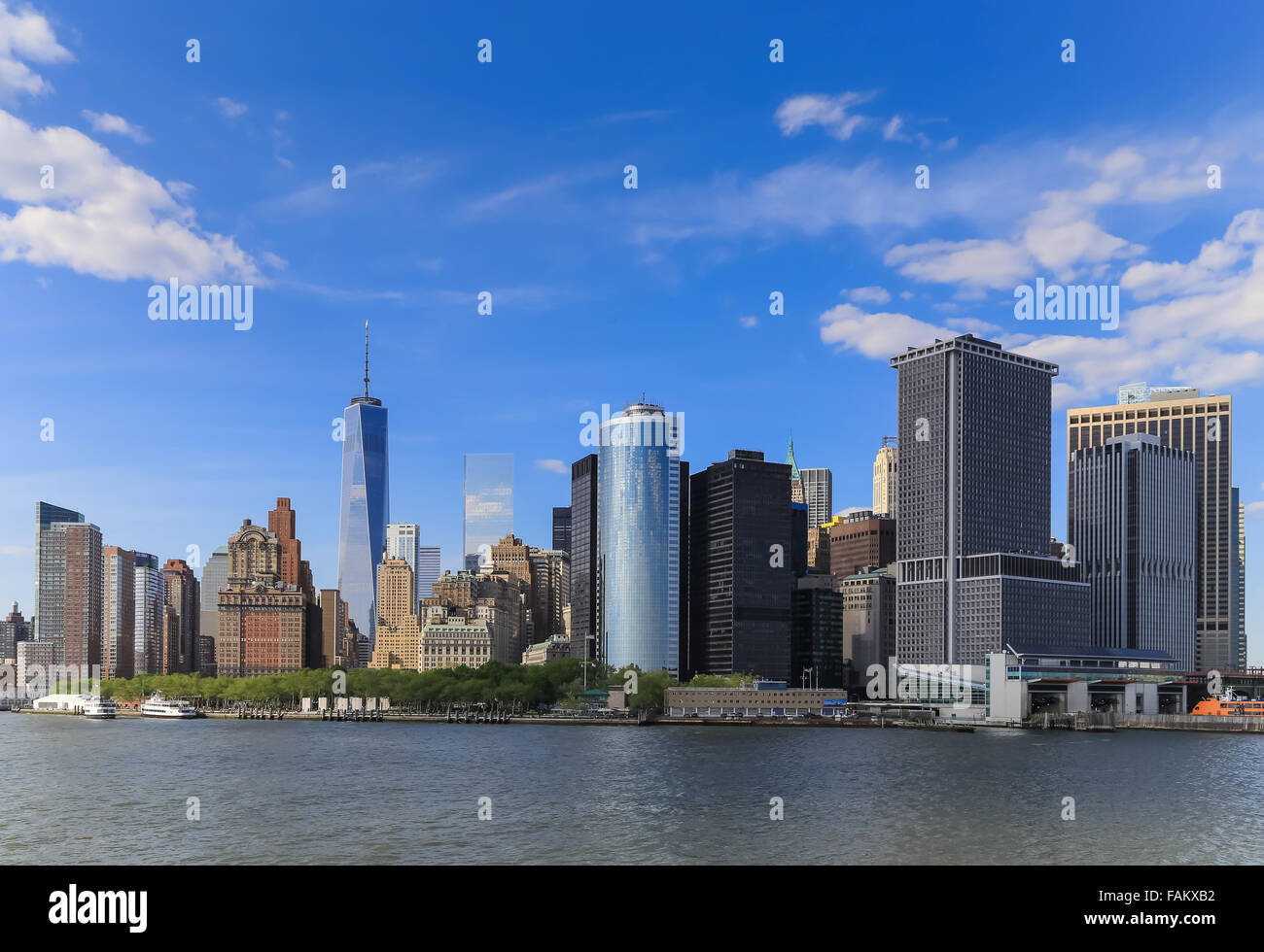 It's a view of Manhattan, New York City during the sunny day with a blue sky and riverside. There are many important building an Stock Photo