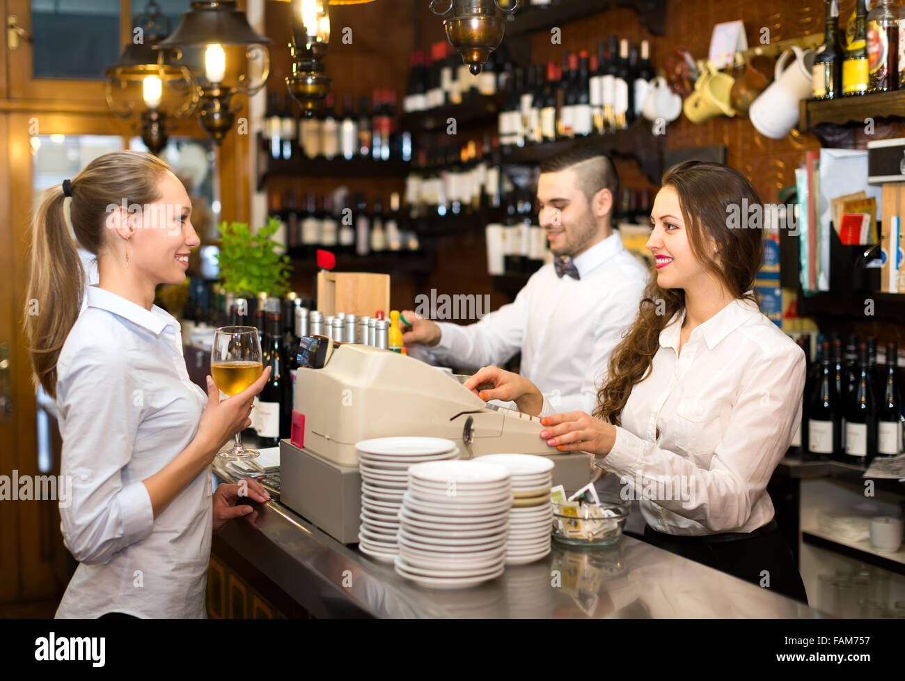 People working at a bar waiter is holding a glass of wine, bartender