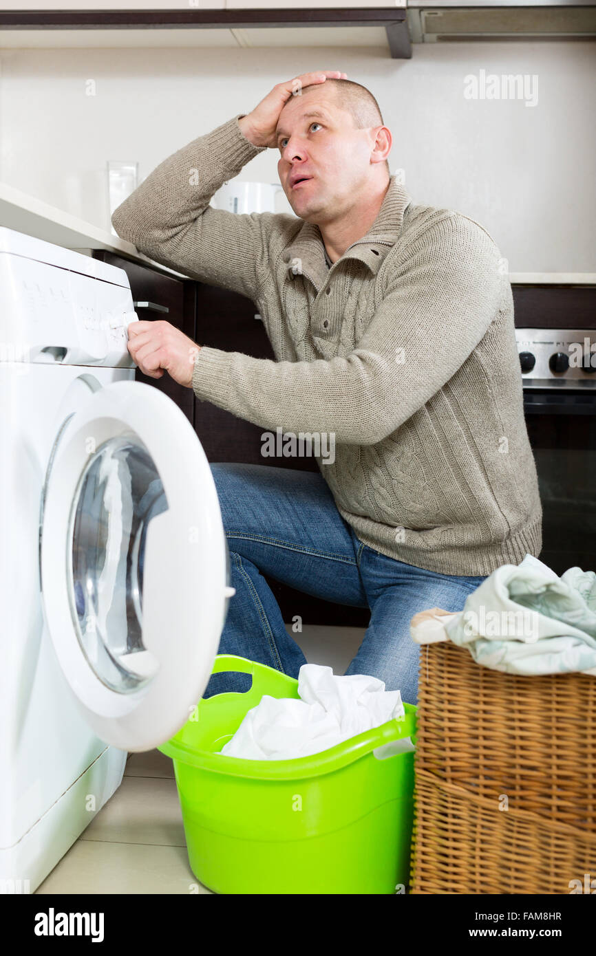 Home laundry. Sad guy using washing machine at home Stock Photo Alamy