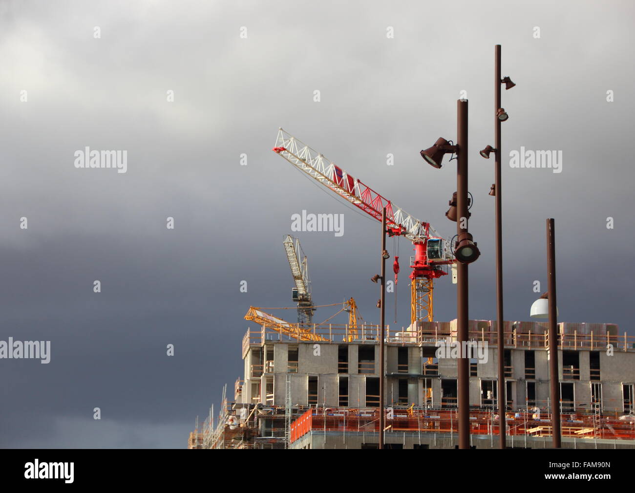 Building Site Cranes and Street Lamps with Dark Clouds Stock Photo