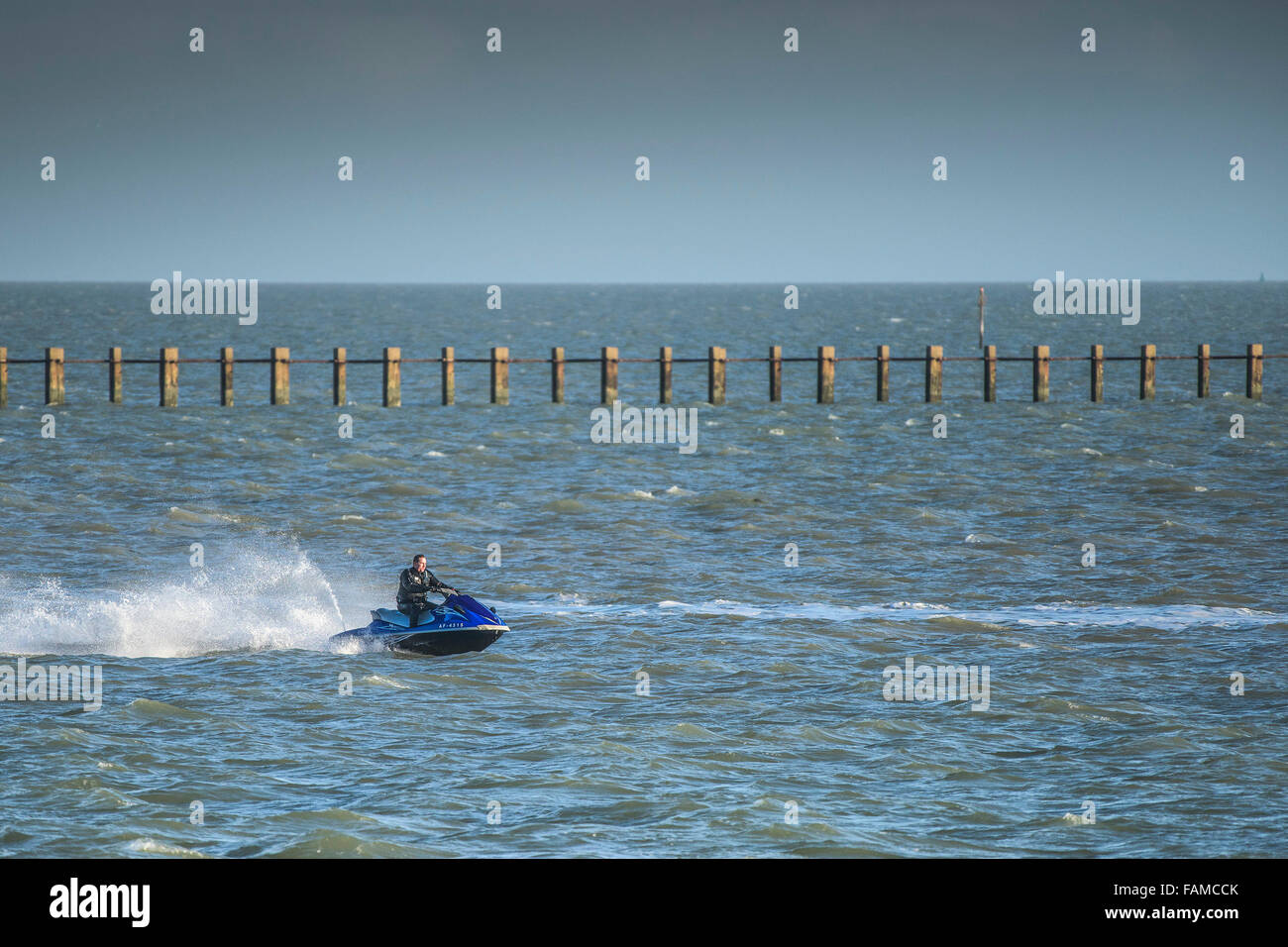 A jetskier speeds past the historic Shoebury Boom off the Essex coast, UK. Stock Photo