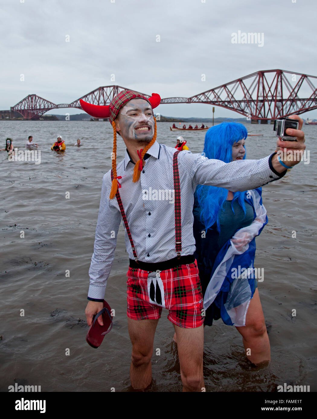 South Queensferry, Edinburgh, Scotland UK. 01 January 2016. Queensferry Loony Dook, the annual dip in the River Forth in the shadow of the world-famous Forth Rail Bridge. Takes place on the third day of the Edinburgh Hogmany New Year celebrations. The weather was fair but chilly between 2-4 degrees but this did not dampen the spirits of these hardy participants. Stock Photo