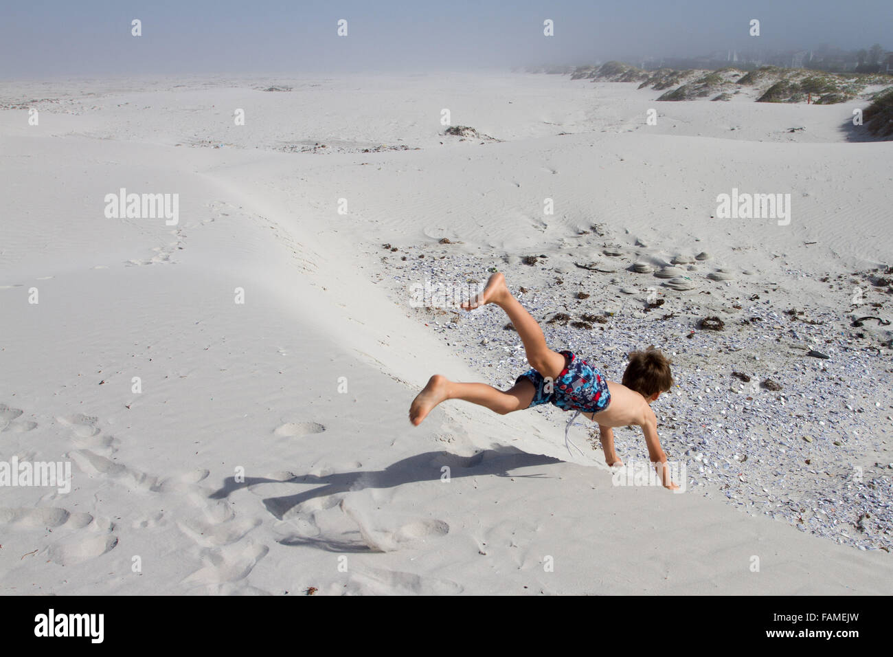 Boy jumps off a sand dune Stock Photo