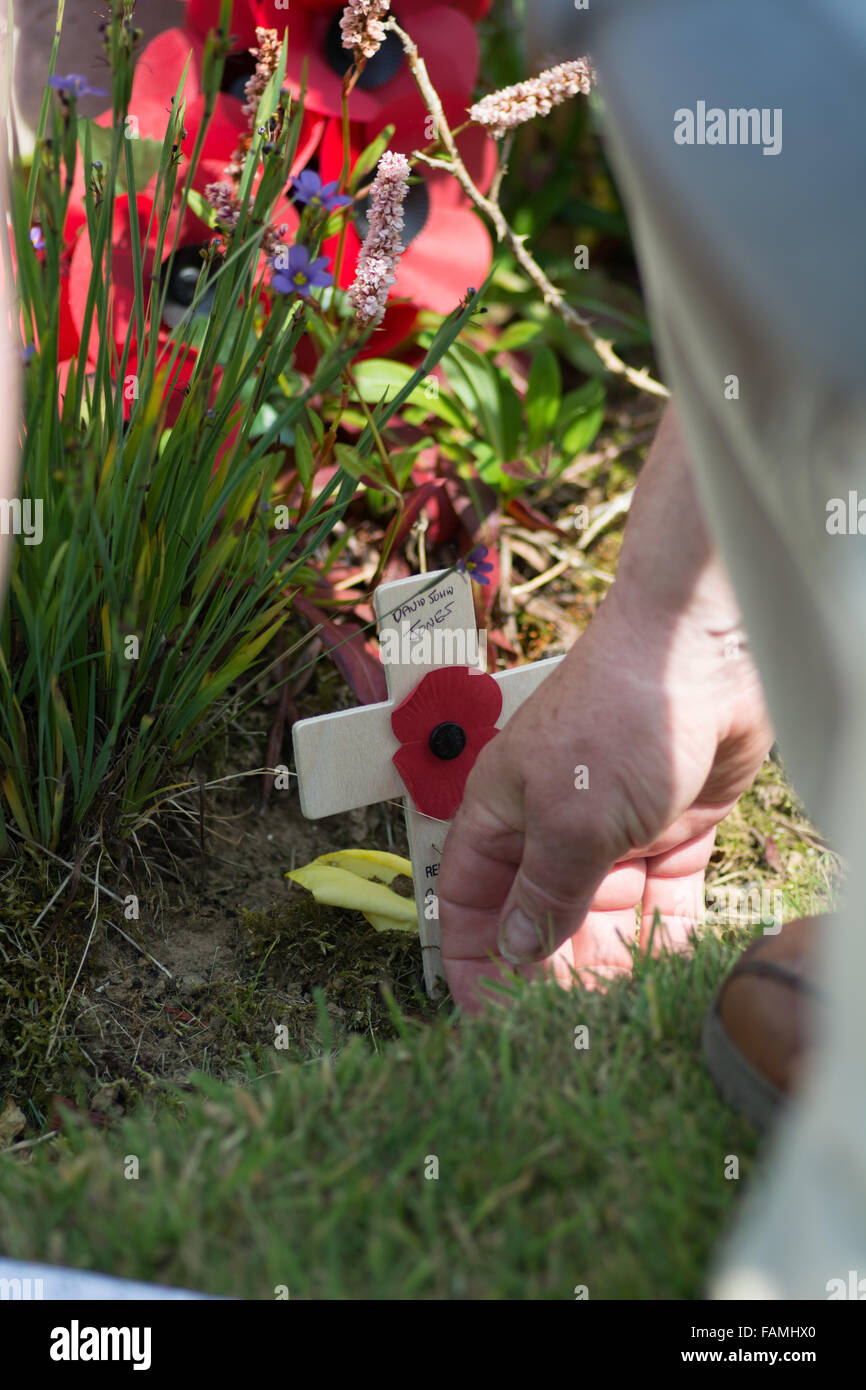 A man lays a cross at a relatives grave in France Stock Photo
