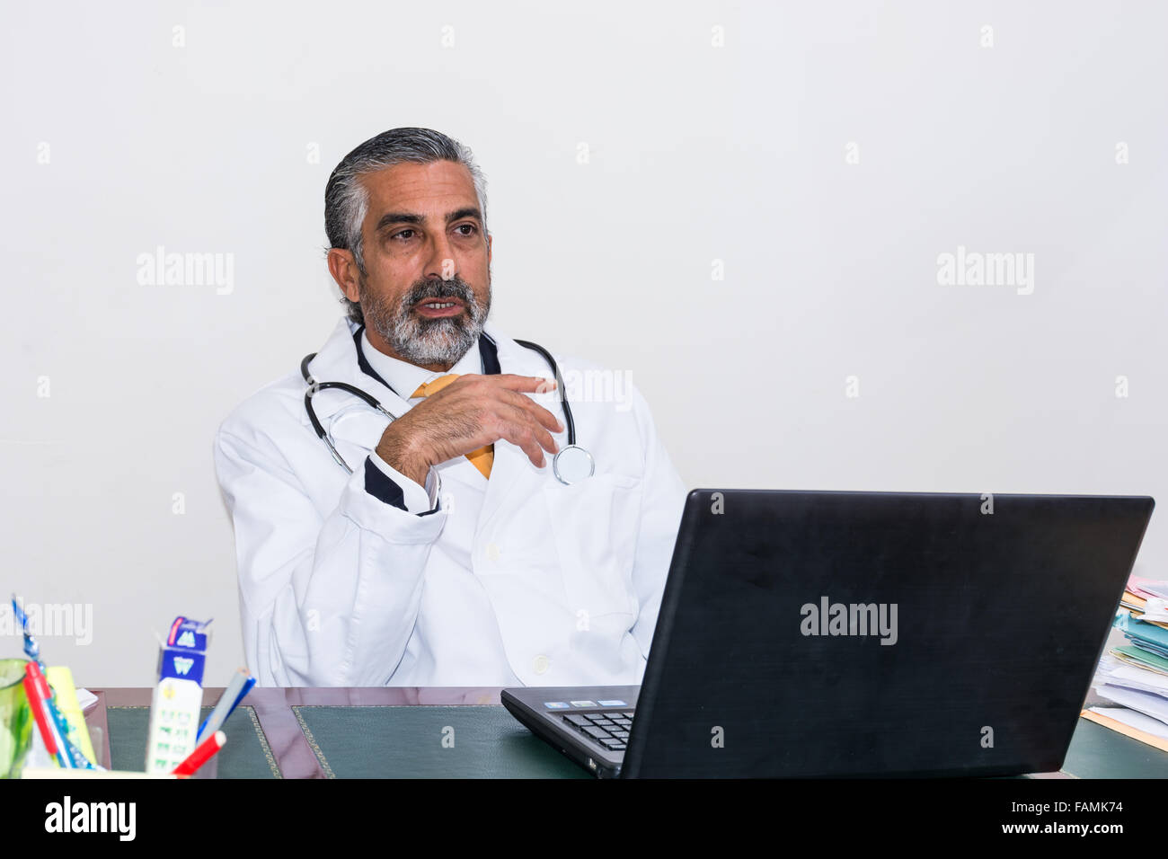 Doctor uses the laptop in his studio. Even doctors and medicals, like other professionals, use new technology such as a laptop. Stock Photo