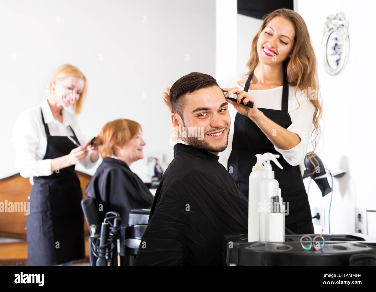 Smiling Young Guy Cuts Hair And Female Barber At The Hair Salon