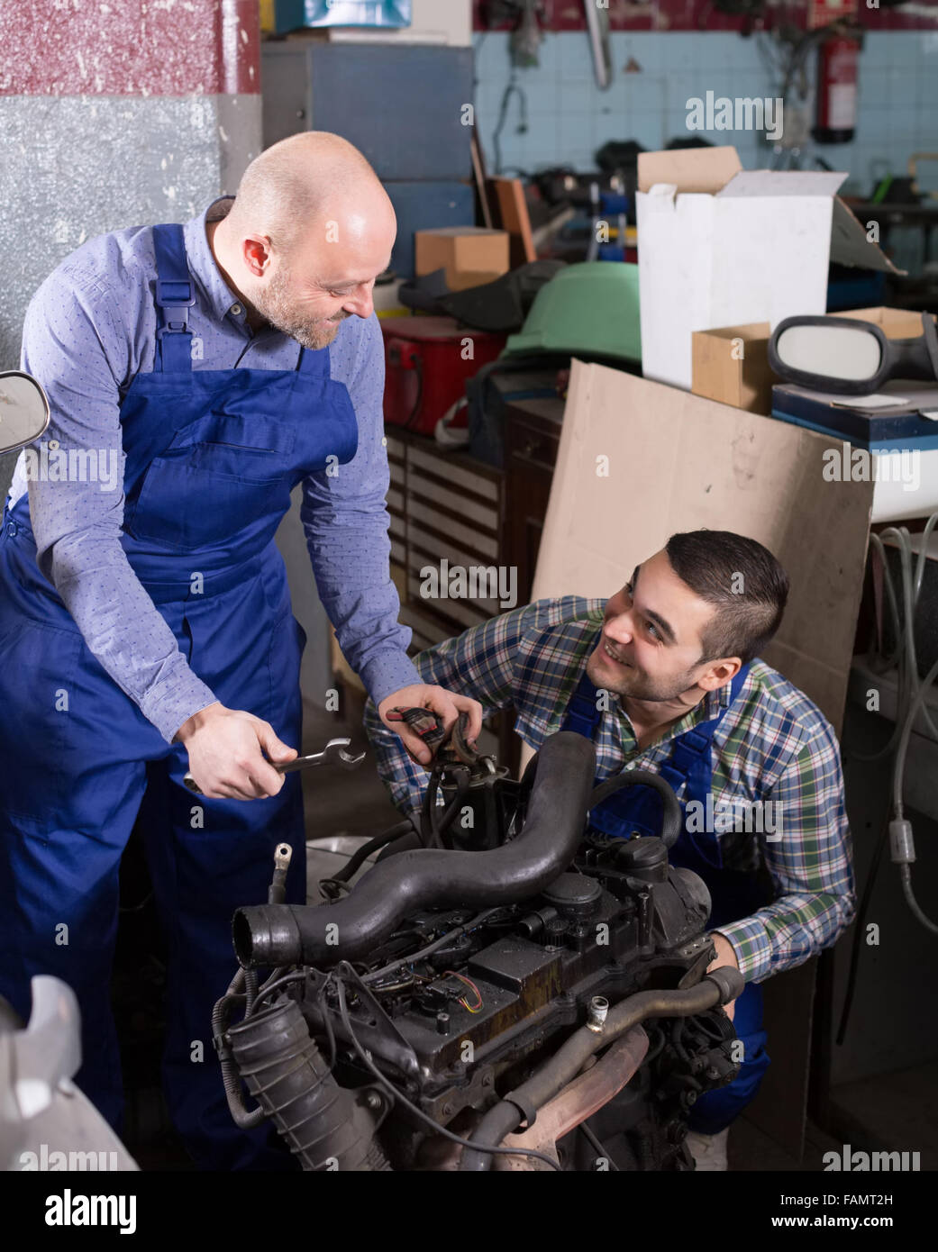 smiling adult car mechanics  working at carshop Stock Photo