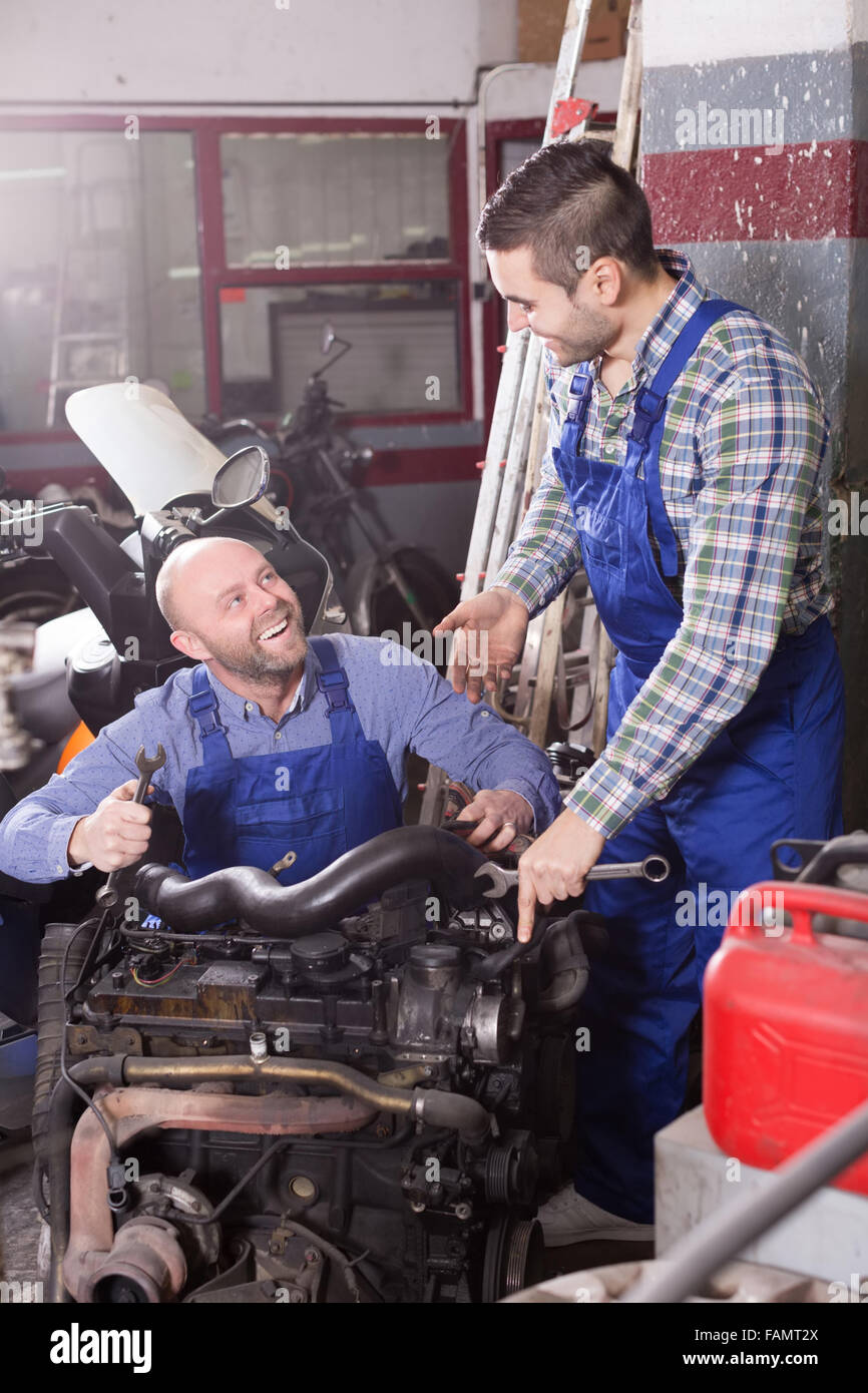 happy russian car mechanics in coveralls working at carshop Stock Photo