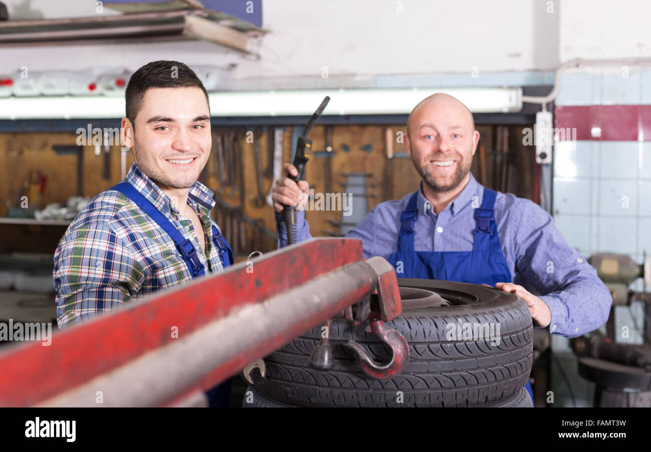 adult american smiling car mechanics in coveralls working at carshop Stock Photo