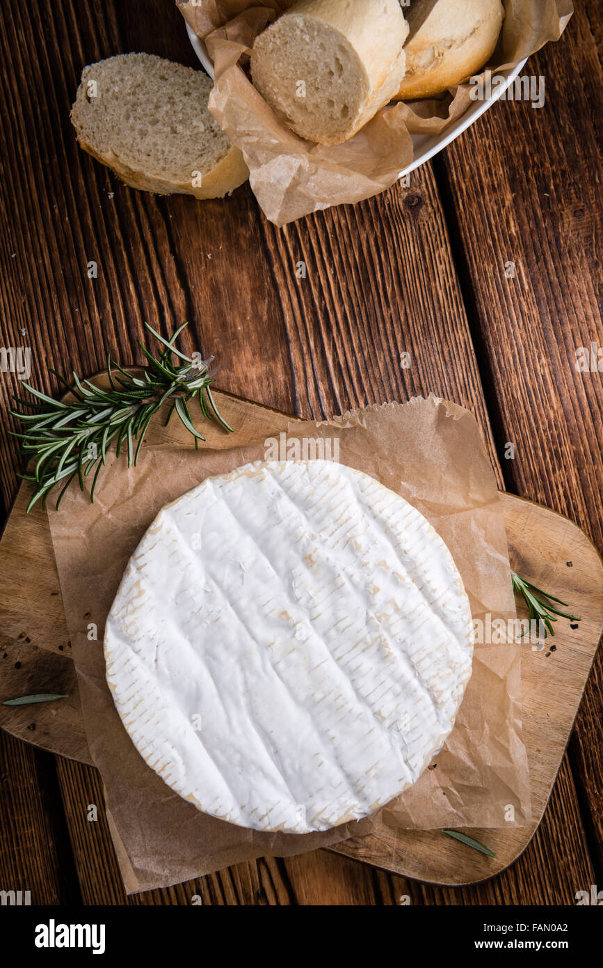 Portion of creamy Camembert (detailed close-up shot) on rustic wooden ...