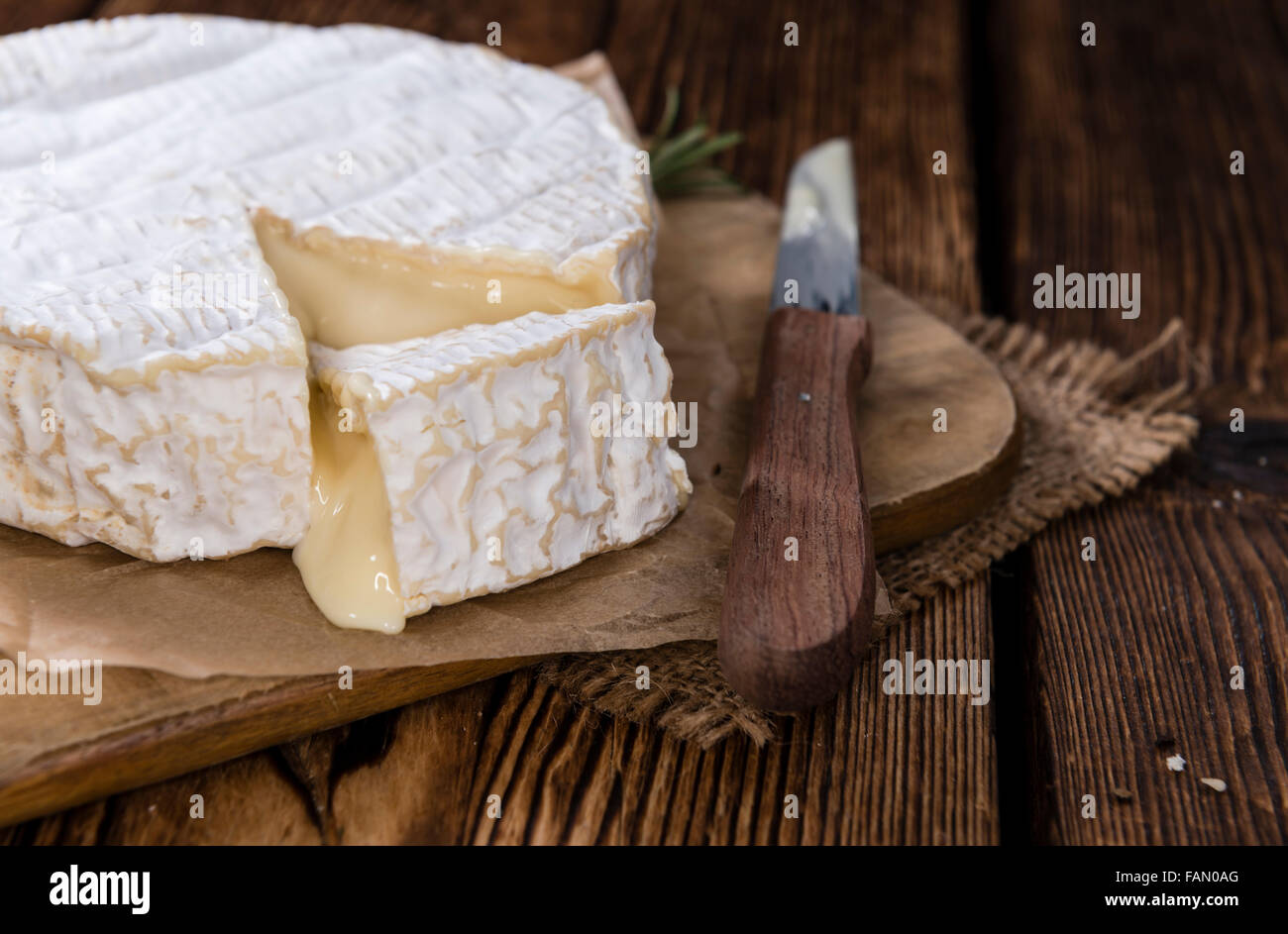 Portion of creamy Camembert (detailed close-up shot) on rustic wooden ...