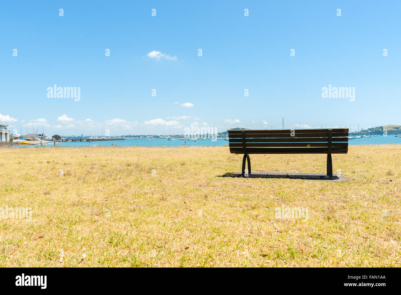 Empty bench seat in the bay. Summer day view of bay, Orakei Auckland, New Zealand. Stock Photo