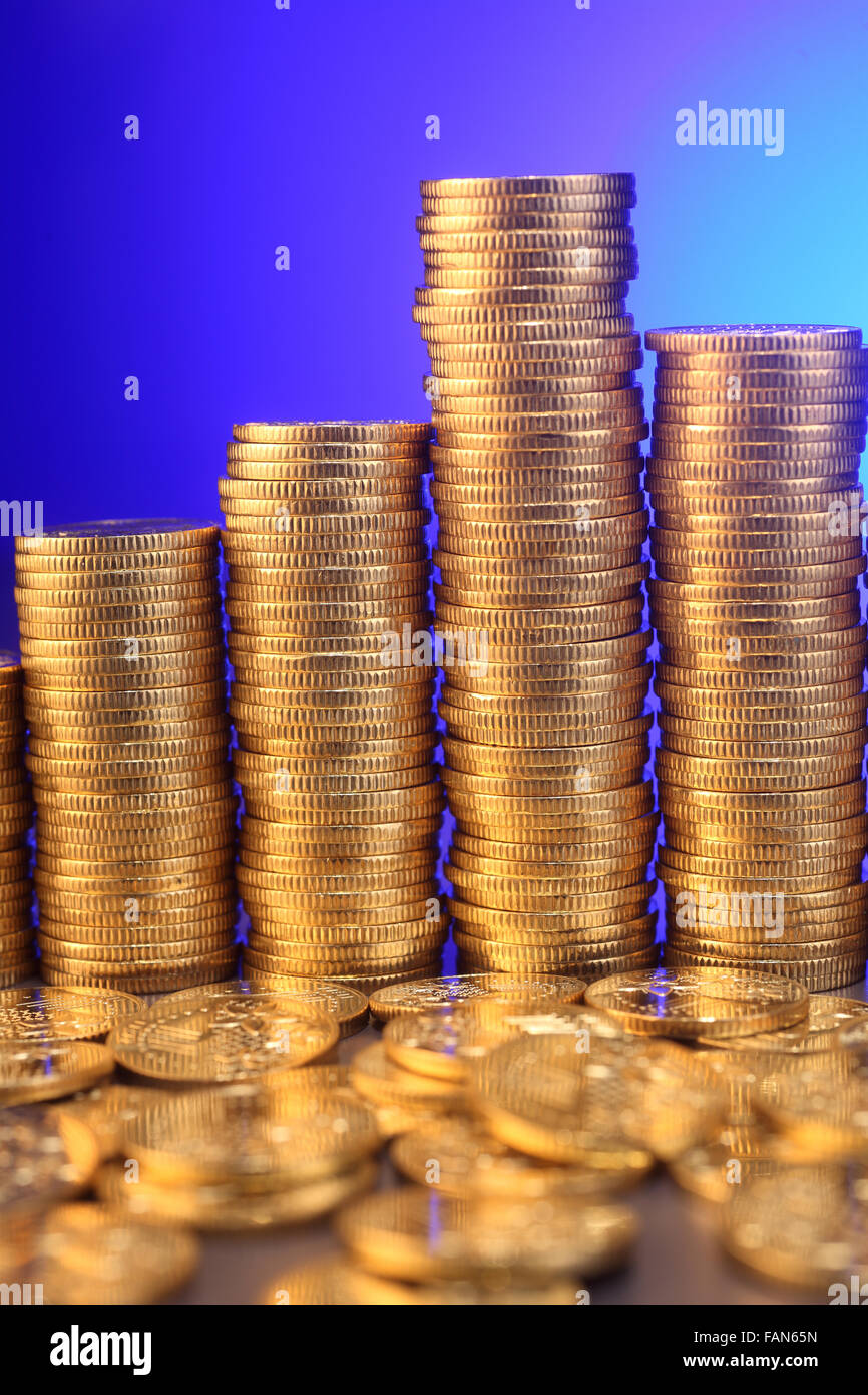 Piles of coins on the blue background Stock Photo - Alamy