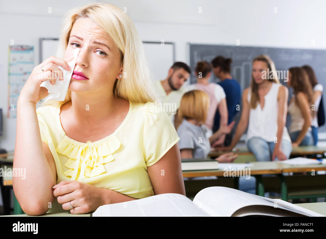 Lonely student with sad expression sits at her desk in the classroom ...
