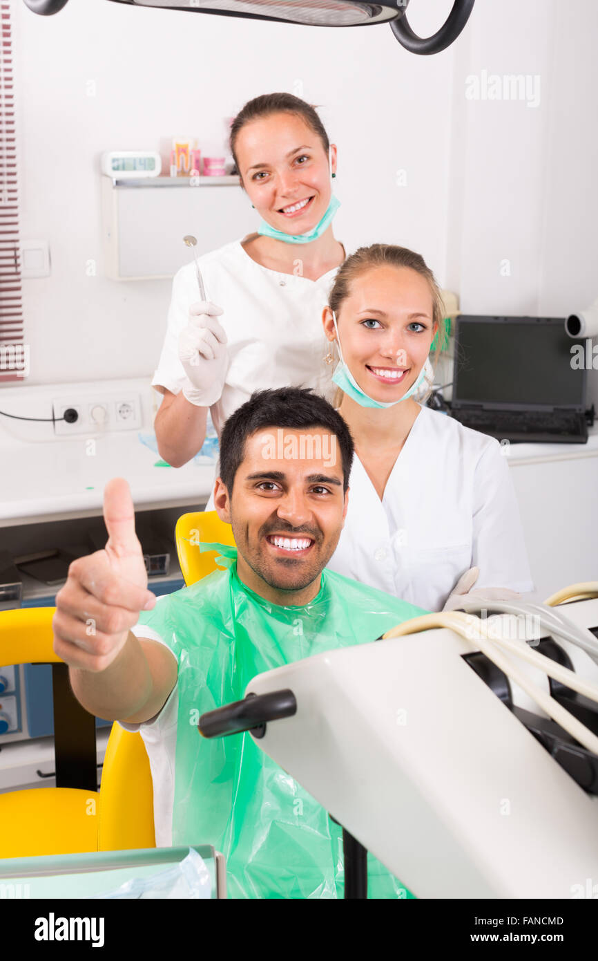 Smiling contented patient giving thumbs up at dentist office Stock