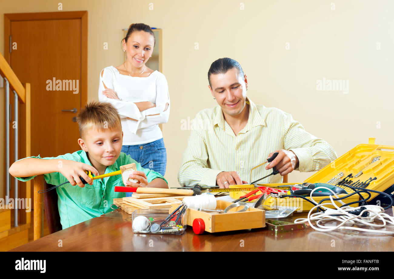 Teenager boy doing something with working tools, parents are watching at home Stock Photo