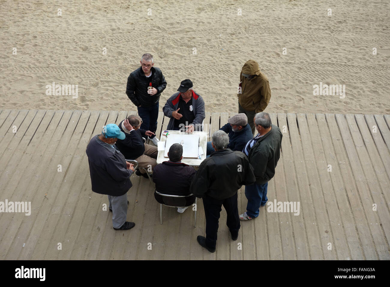 Group of retired men playing dominoes by Barcelona beach Stock Photo