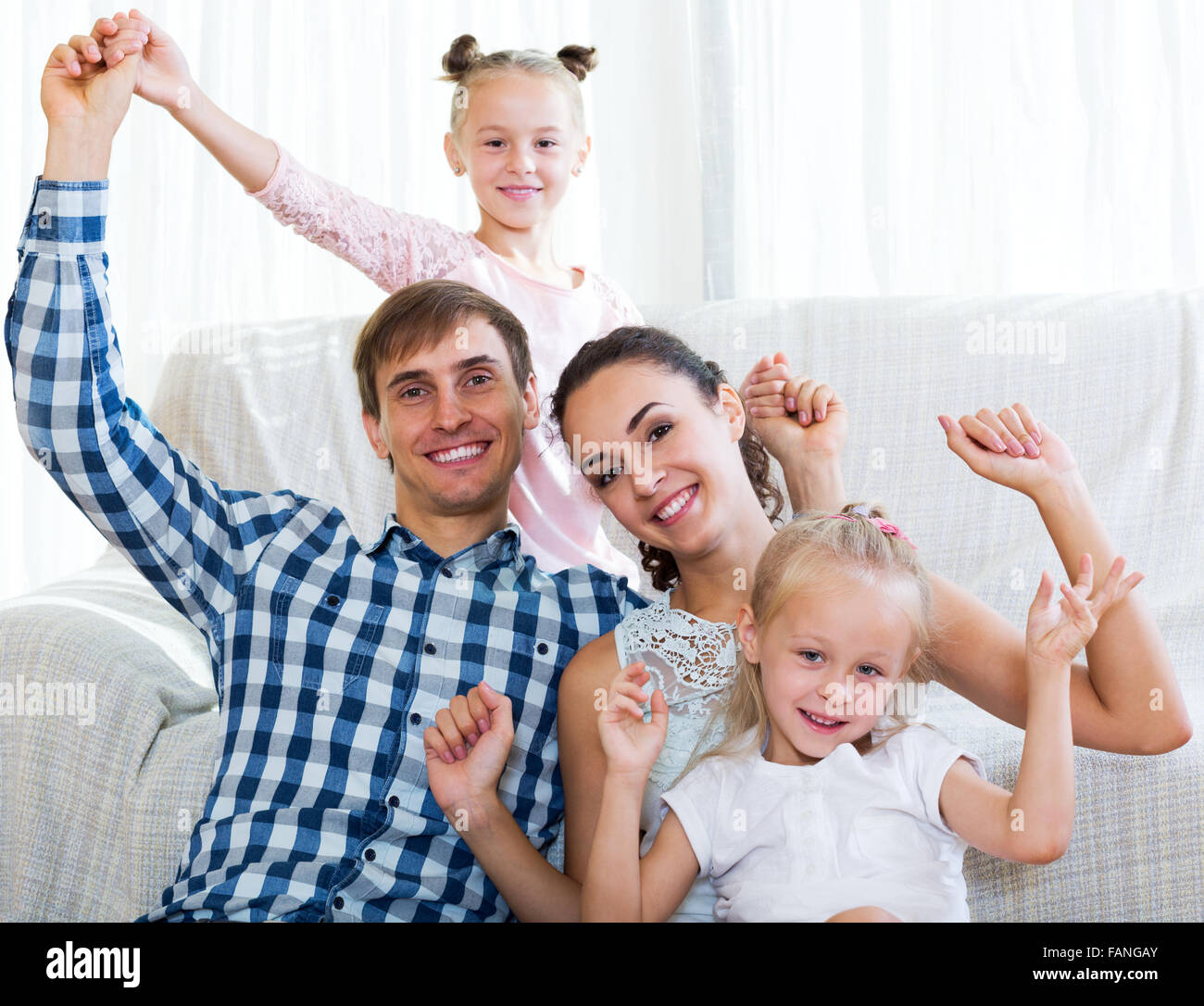 Smiling parents with two daughters relaxing at home Stock Photo - Alamy