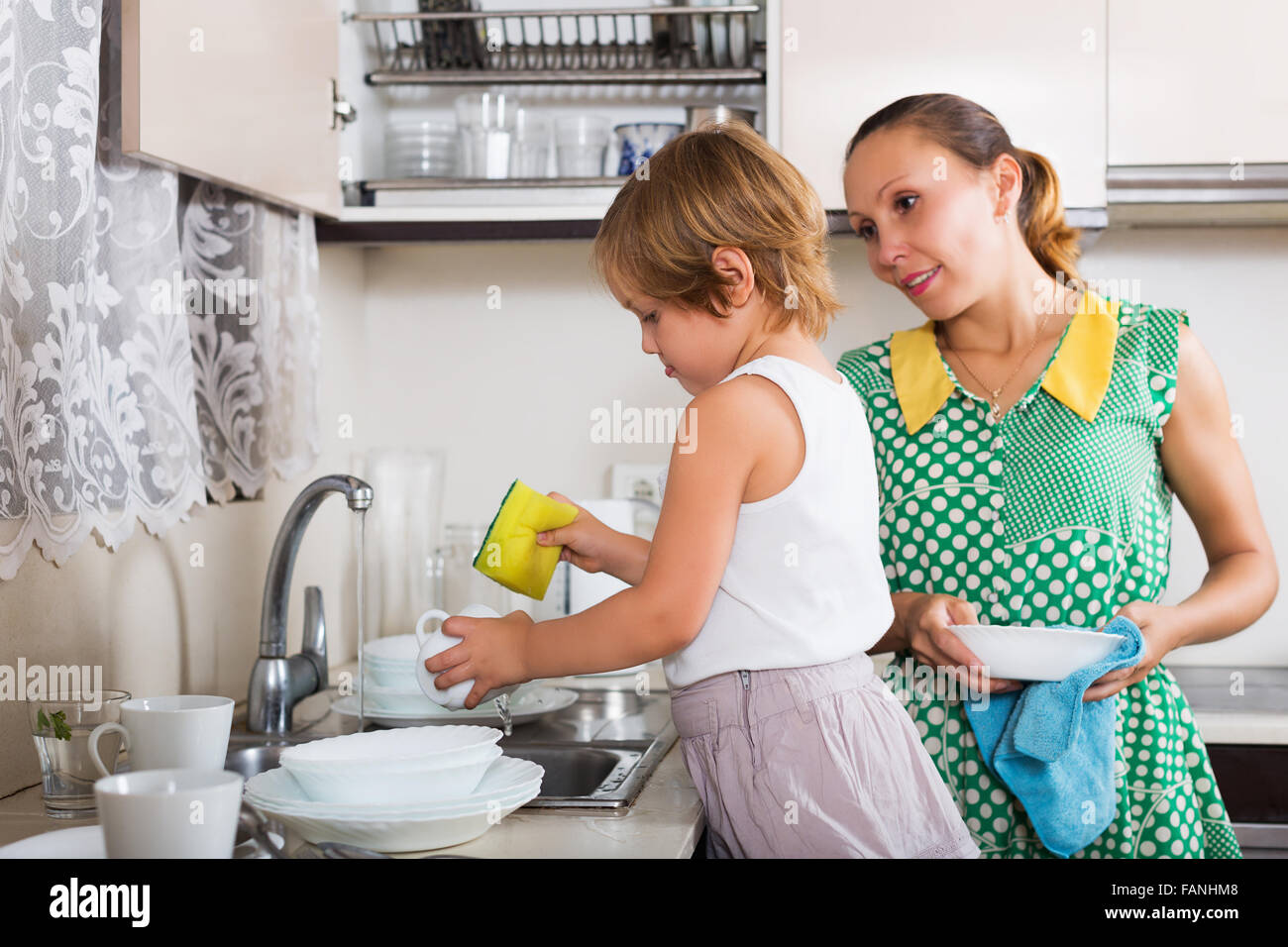 Baby girl with woman washing dishes in kitchen Stock Photo Alamy