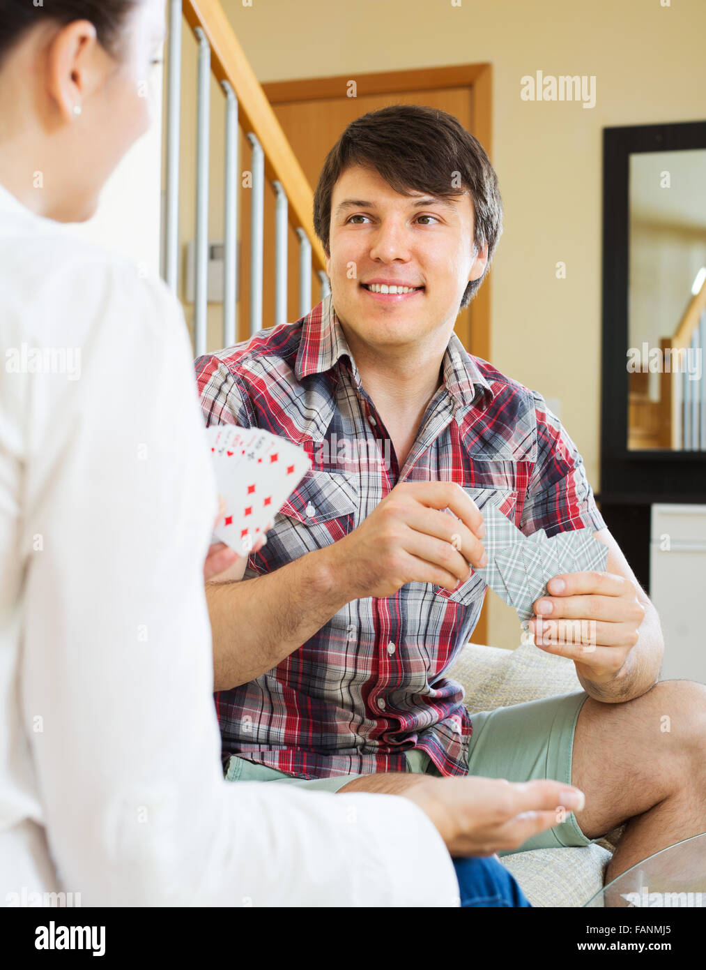 Young happy couple playing cards and talking at home interior Stock ...
