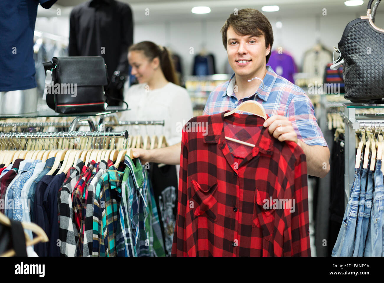 Smiling man choosing shirts in an outlet clothing store Stock Photo - Alamy