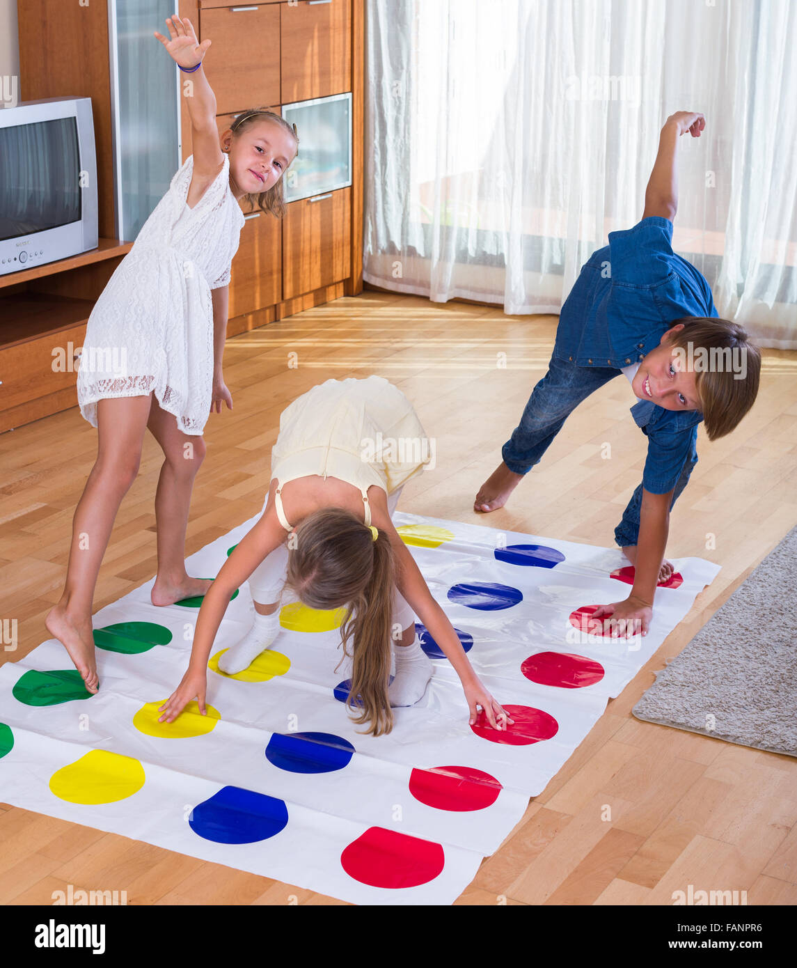 Group of happy children playing at twister inside Stock Photo