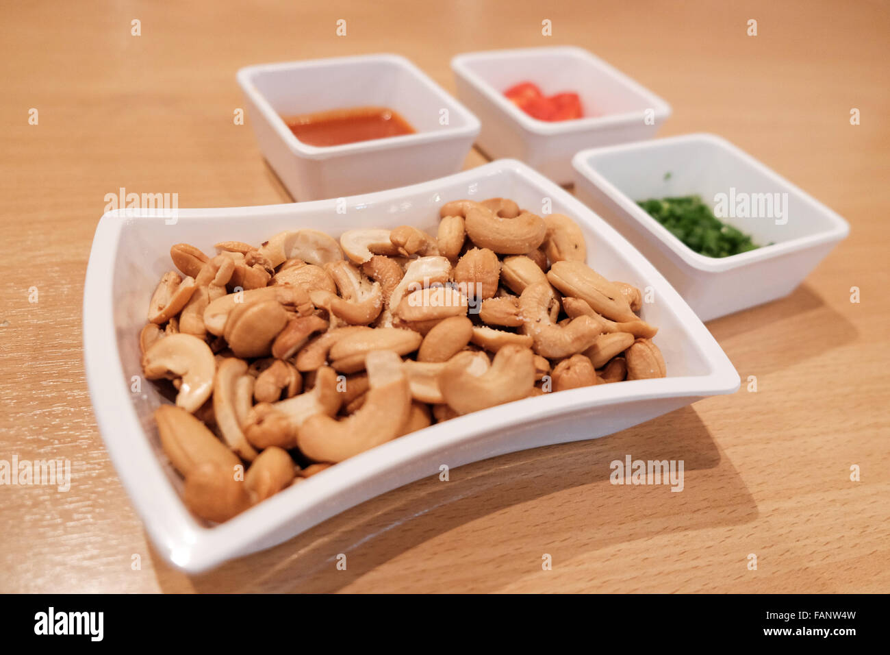 Salted cashew nuts with dippings on wooden table Stock Photo