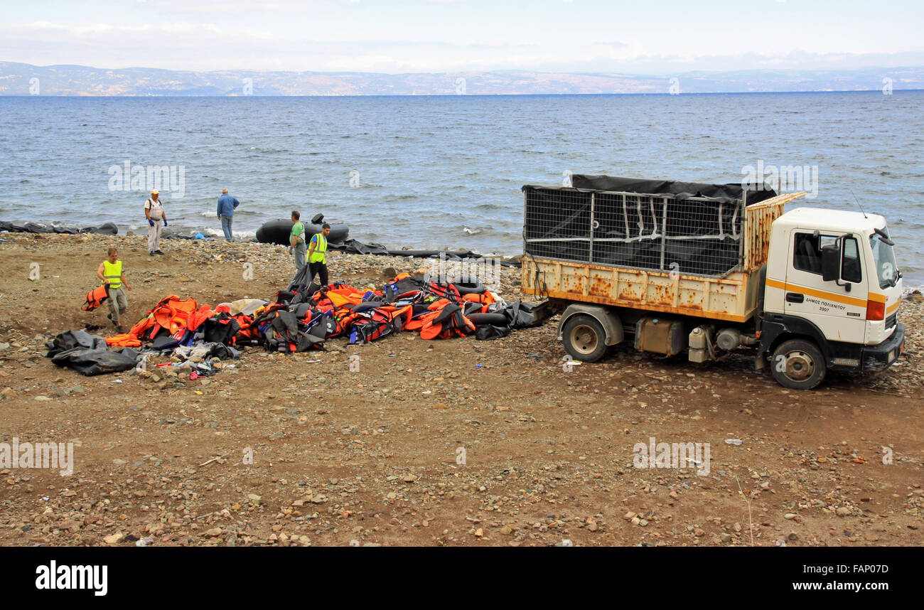 Workmen cleaning up  rubbish  and disregarded life jackets after the arrival of refugees asylum seekers and immigrants on the island of Lesbos Greece Stock Photo