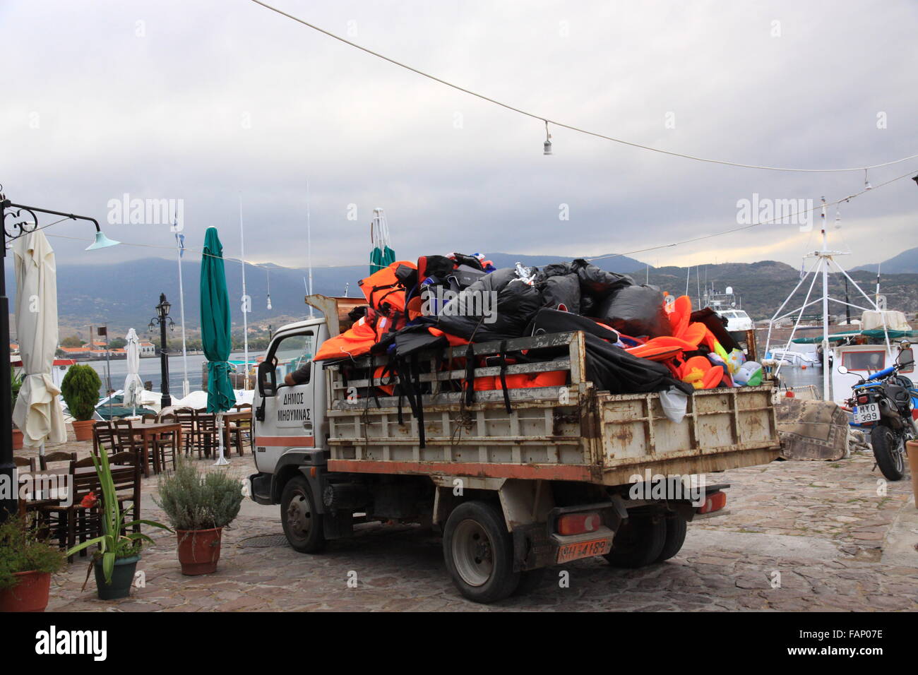 Workmen cleaning up  rubbish  and disregarded life jackets after the arrival of refugees asylum seekers and immigrants on the island of Lesbos Greece Stock Photo