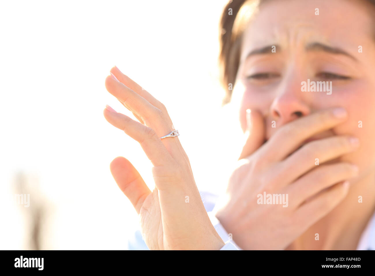 Woman crying while watching an engagement ring after proposal in a sunny day Stock Photo