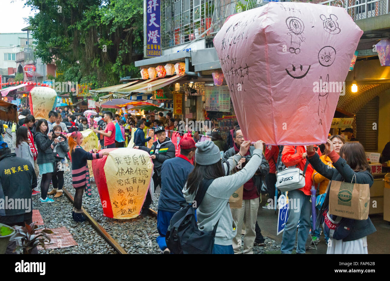 Releasing Sky Lantern written with good wishes during Chinese Lantern Festival, Shifen Old Street, Taiwan Stock Photo