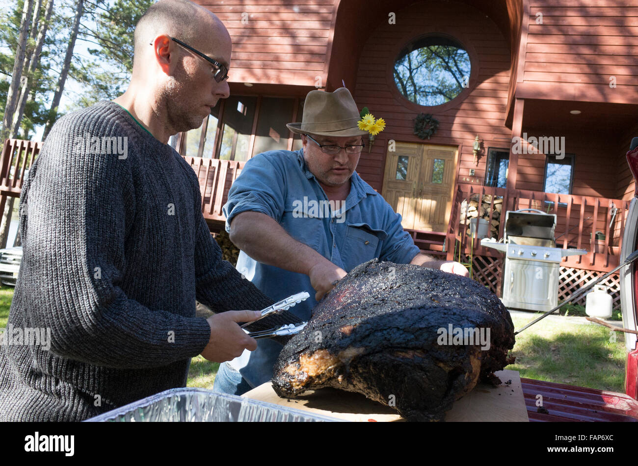 Men preparing large prime rib roast outside at lake cabin for men's weekend fishing retreat. Nisswa Minnesota MN USA Stock Photo