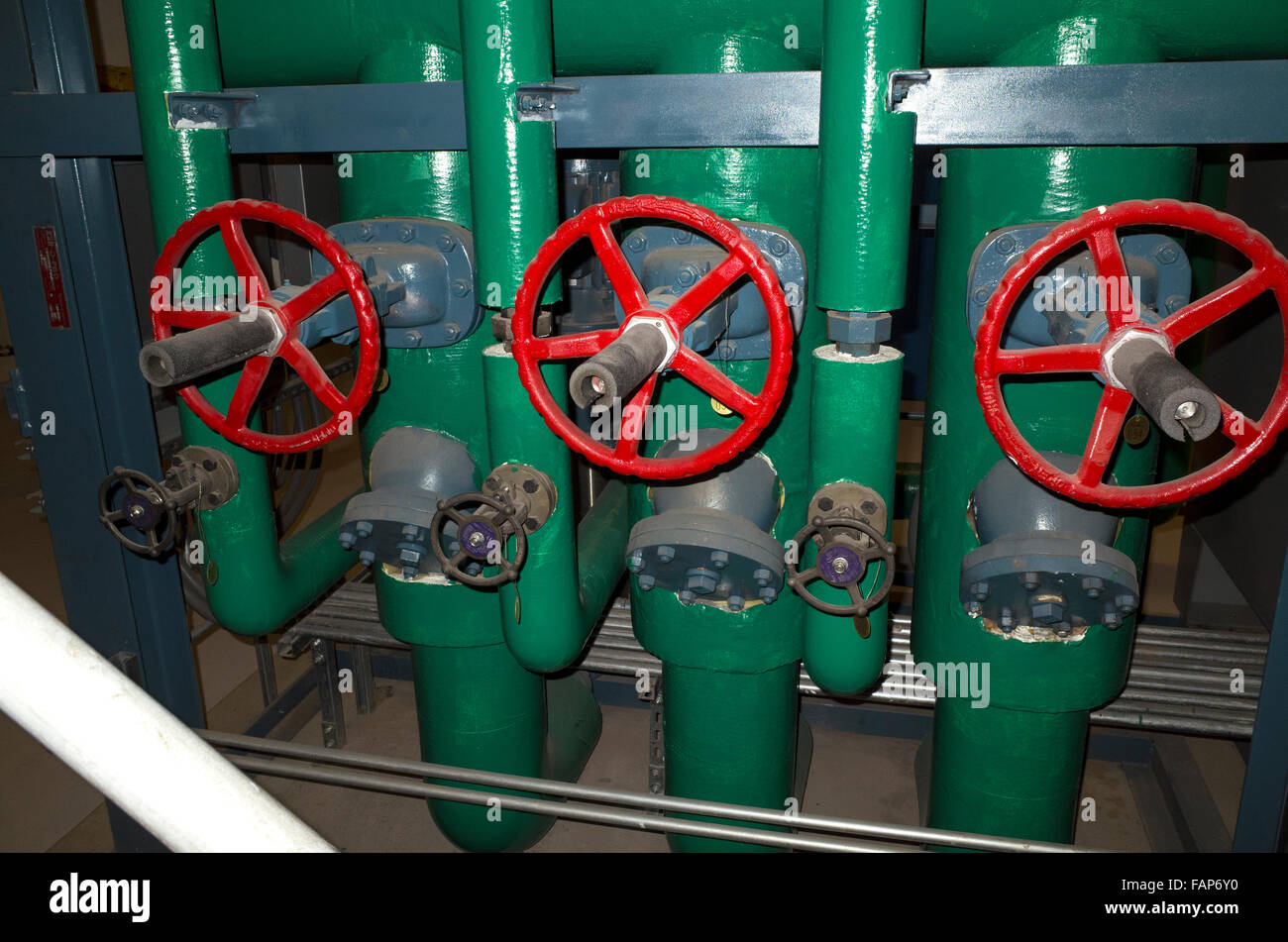 Three large red wheels regulating the heat in large green pipes. Macalester College heating plant. St Paul Minnesota MN USA Stock Photo