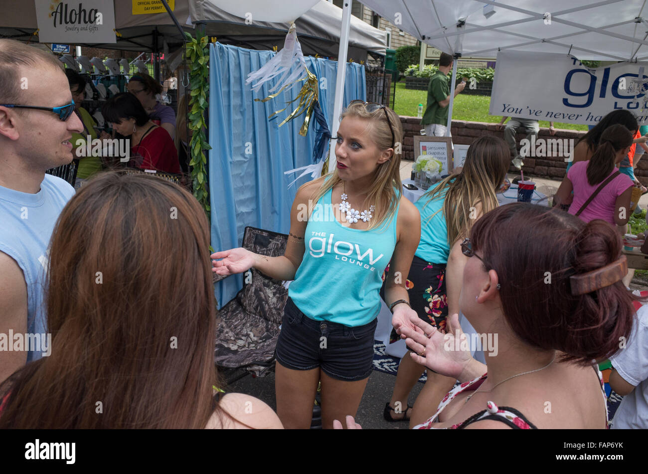 Woman describing the benefits of The Glow Lounge sunless tanning studio. Grand Old Day Street Fair. St Paul Minnesota MN USA Stock Photo