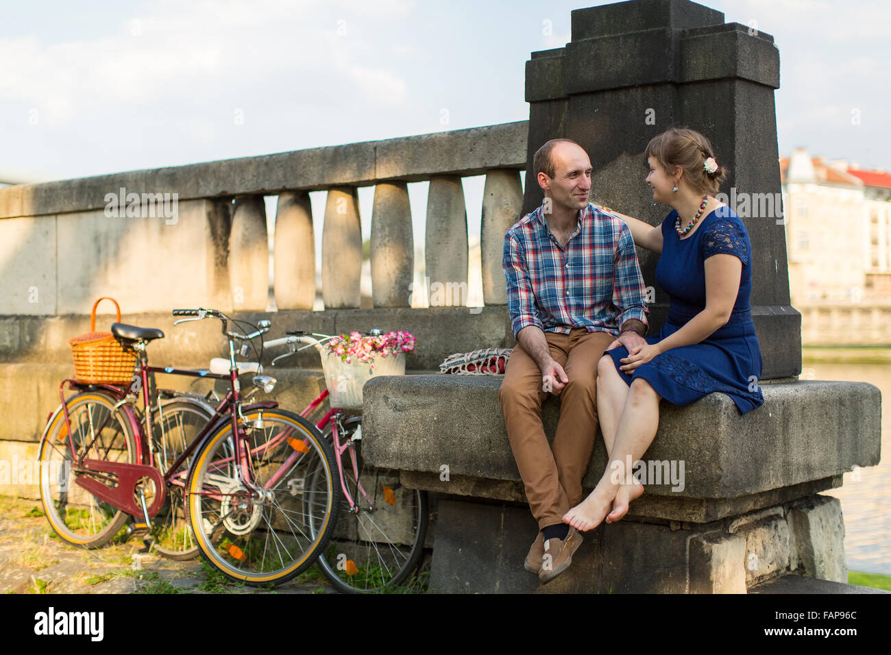 Young couple with bicycles sitting on the parapet. Stock Photo