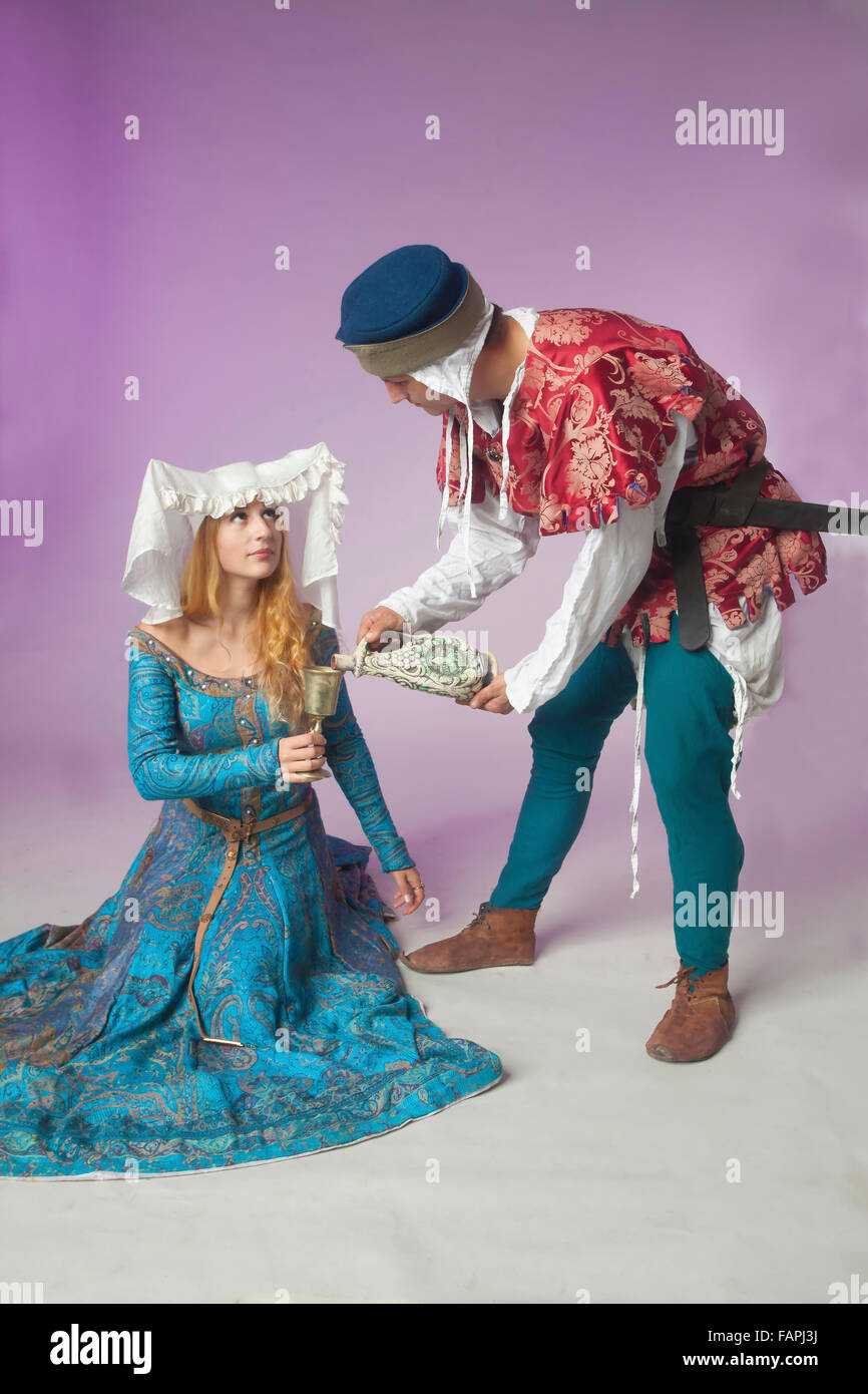 Studio shot of young couple dressed in medieval costumes as a beautiful  noble lady and a courting man pouring vine Stock Photo - Alamy
