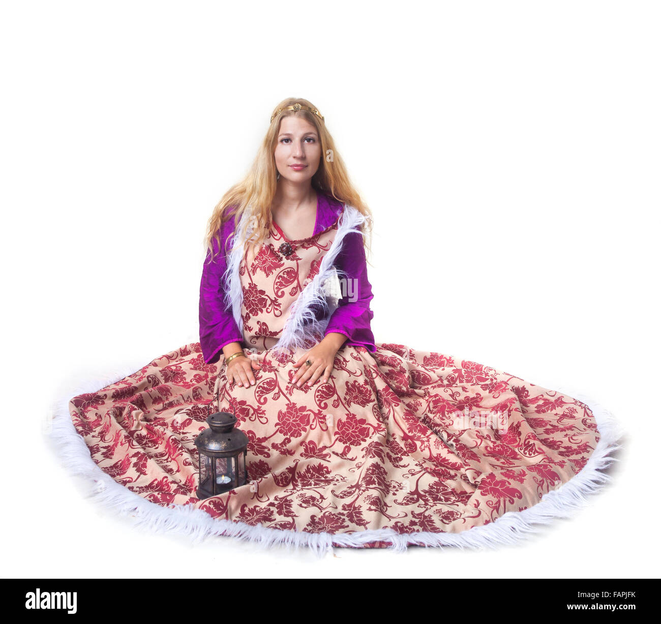 Studio shot of beautiful young girl dressed in Medieval warm dress sitting on the floor (portrait over white) Stock Photo
