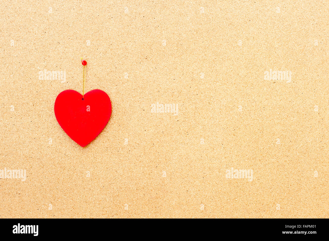 Valentine's day red heart pinned on left side on wooden cork board Stock Photo