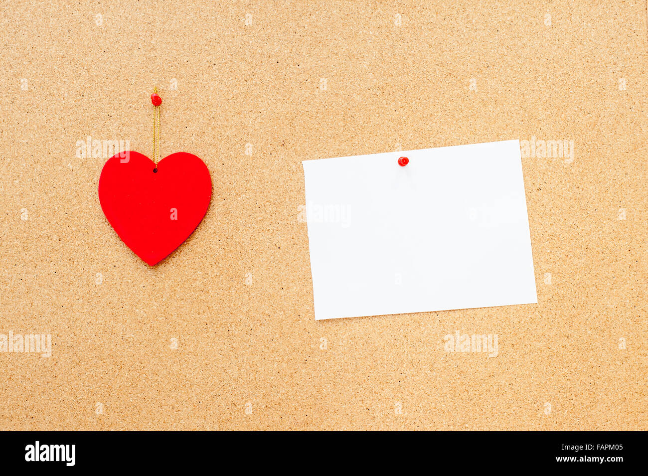 Valentine's day red heart and white empty card pinned on wooden cork board Stock Photo