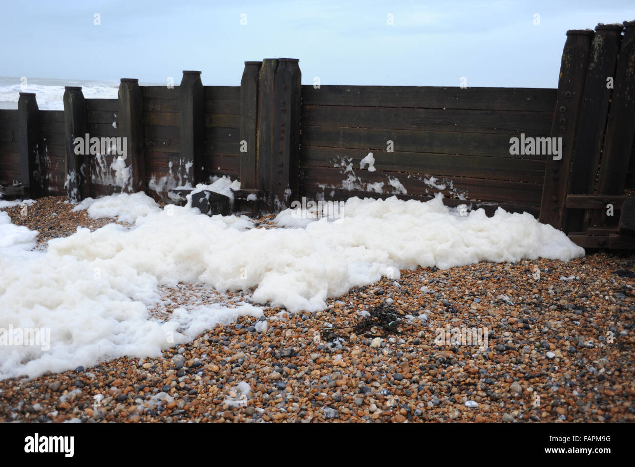 During bad weather and stormy conditions large waves cause foam to appear on the beach in front of Eastbourne Pier in the seaside town of Eastbourne, East Sussex, England. Stock Photo