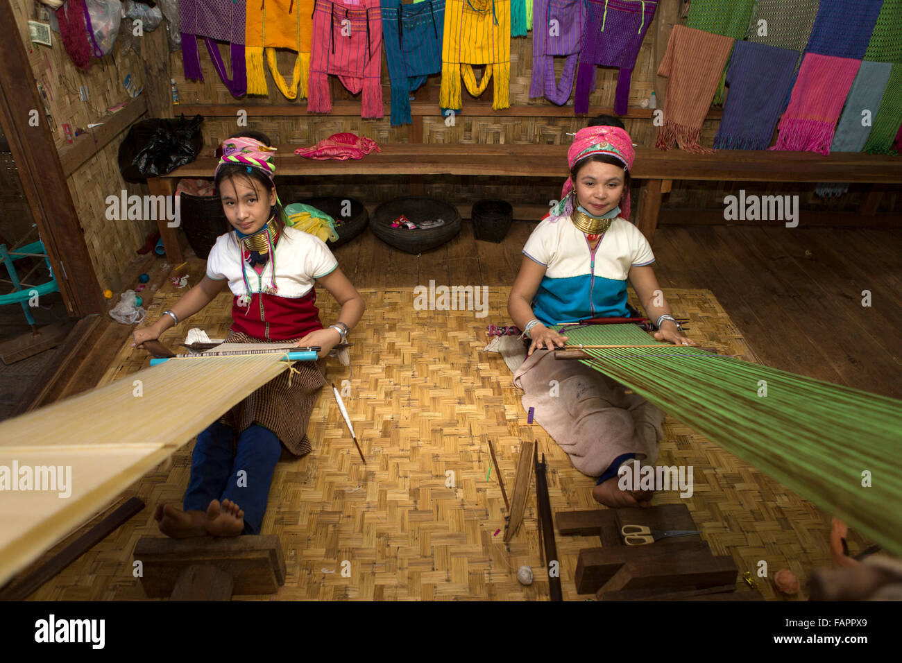 Women from the Kayan tribe weaving in a workshop at Inle Lake in Myanmar (Burma). The women wear brass coils on their necks. Stock Photo