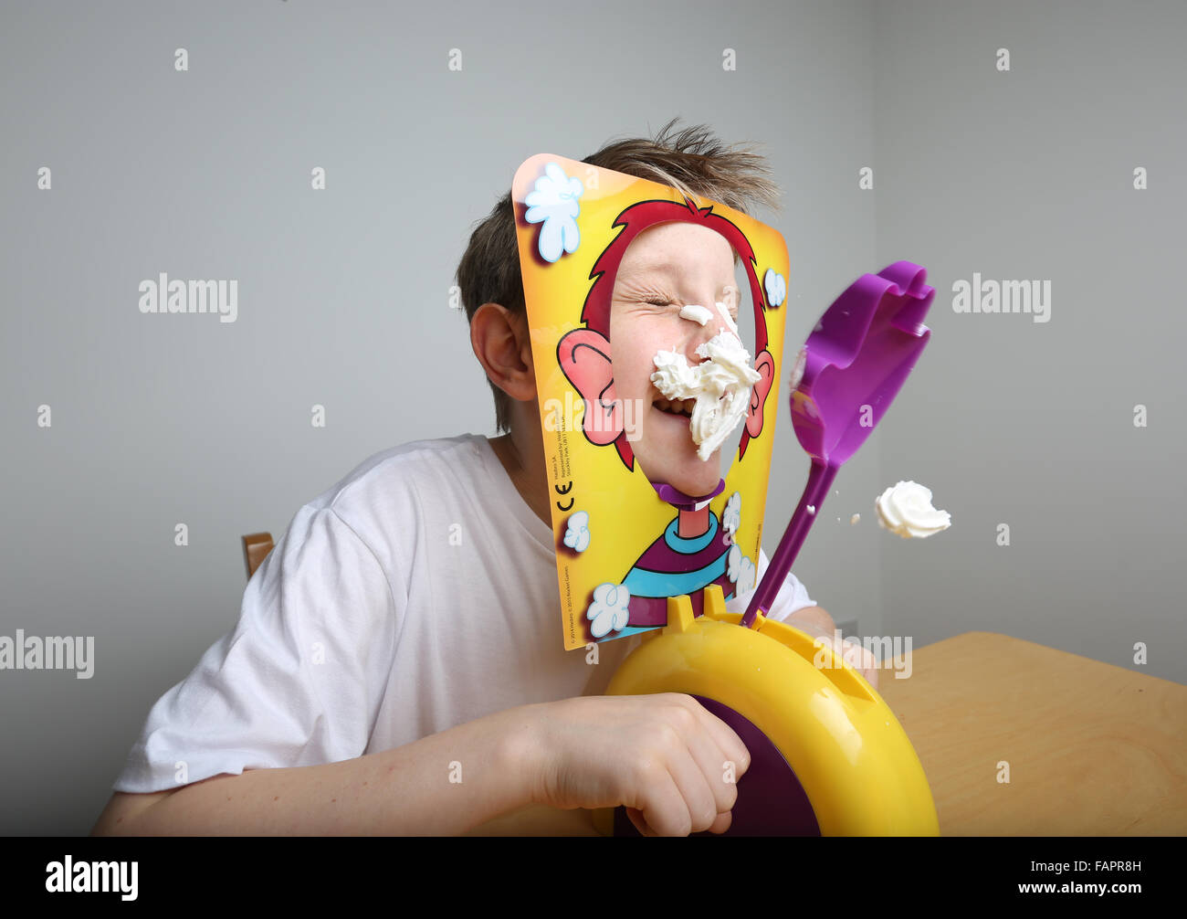 A boy playing the board game Pie Face by Hasbro getting covered in cream Stock Photo