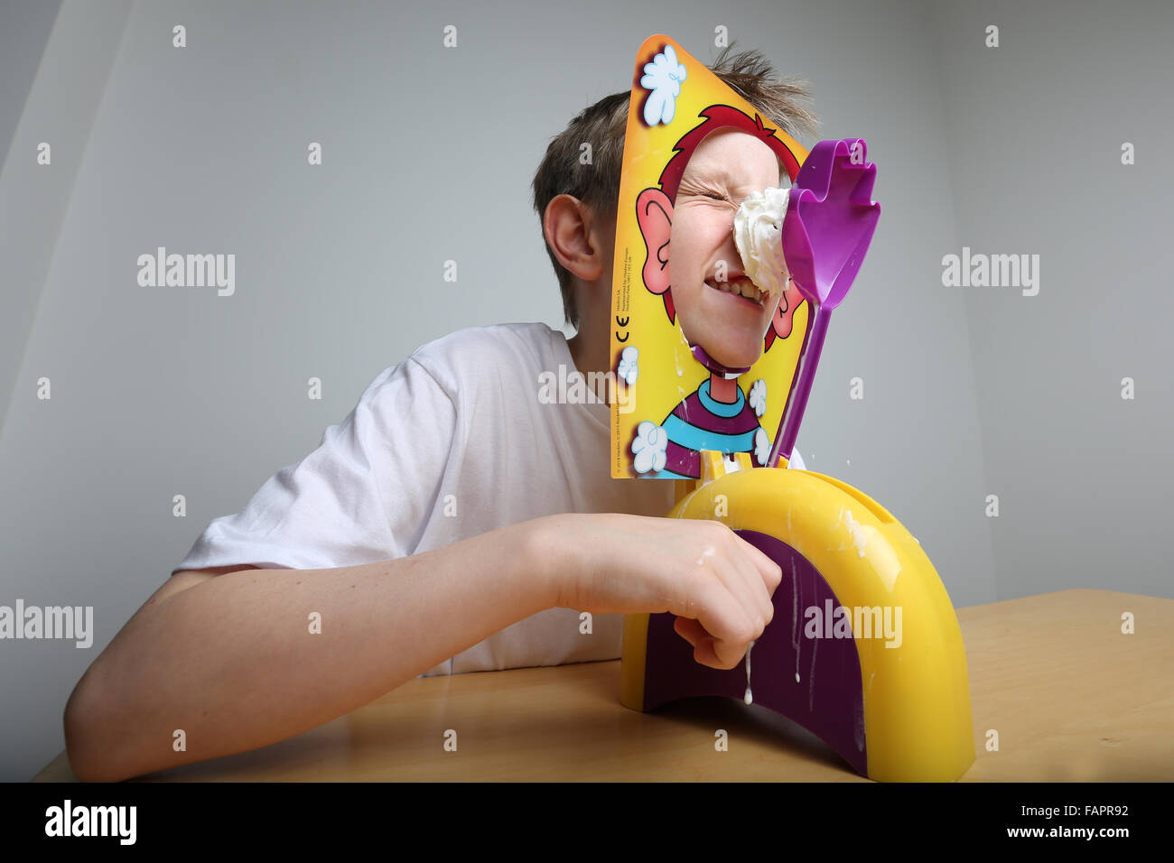 A boy playing the board game Pie Face by Hasbro getting covered in cream Stock Photo