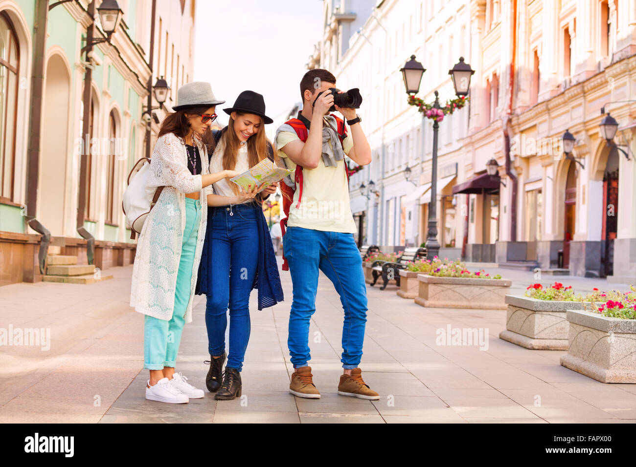Two girls hold city map and guy with camera Stock Photo